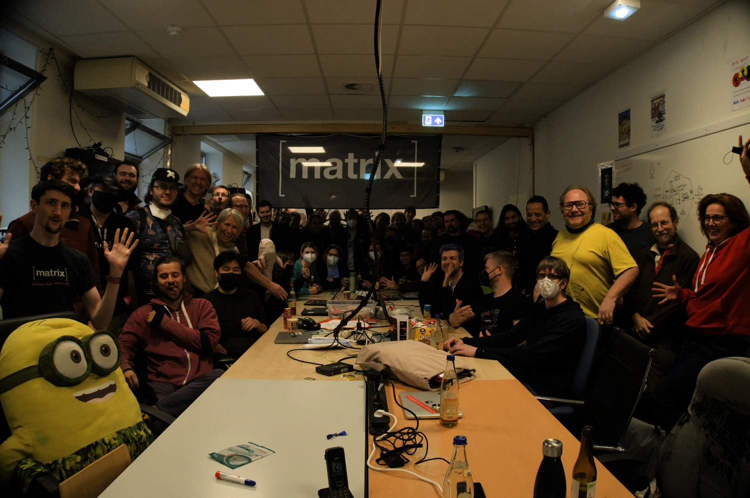 A picture of a group of people smiling and laughing in front of the Matrix flag